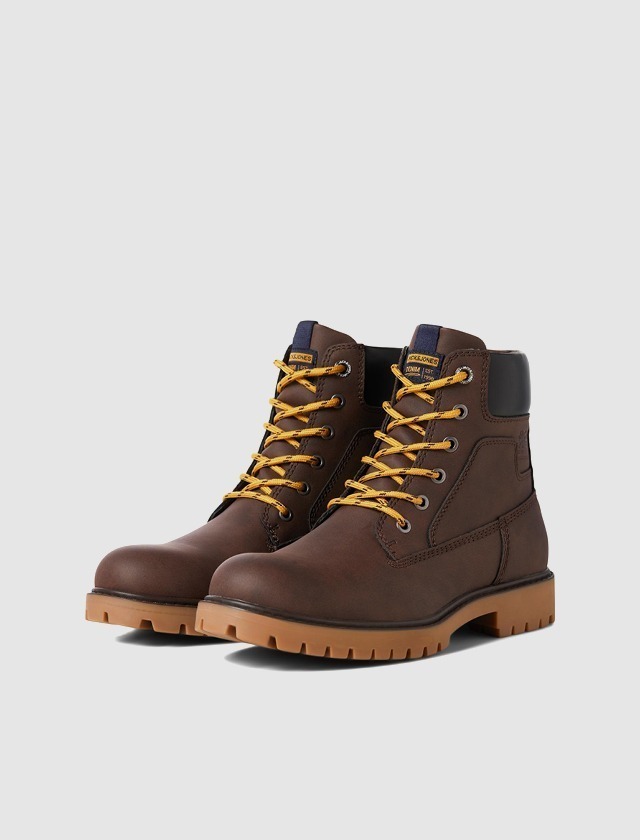 Braune Stiefel mit gelben Schnürsenkeln.