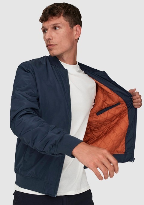 Ein Mann trägt eine navyblaue Jacke mit oranger Innenseite und einem weißen T-Shirt. Ein Mann trägt eine navyblaue Jacke mit oranger Innenseite und einem weißen T-Shirt.