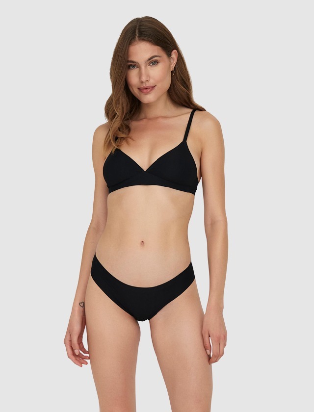 Eine junge Frau trägt einen schwarzen Bikini und steht vor einem neutralen Hintergrund. Eine junge Frau trägt einen schwarzen Bikini und steht vor einem neutralen Hintergrund.