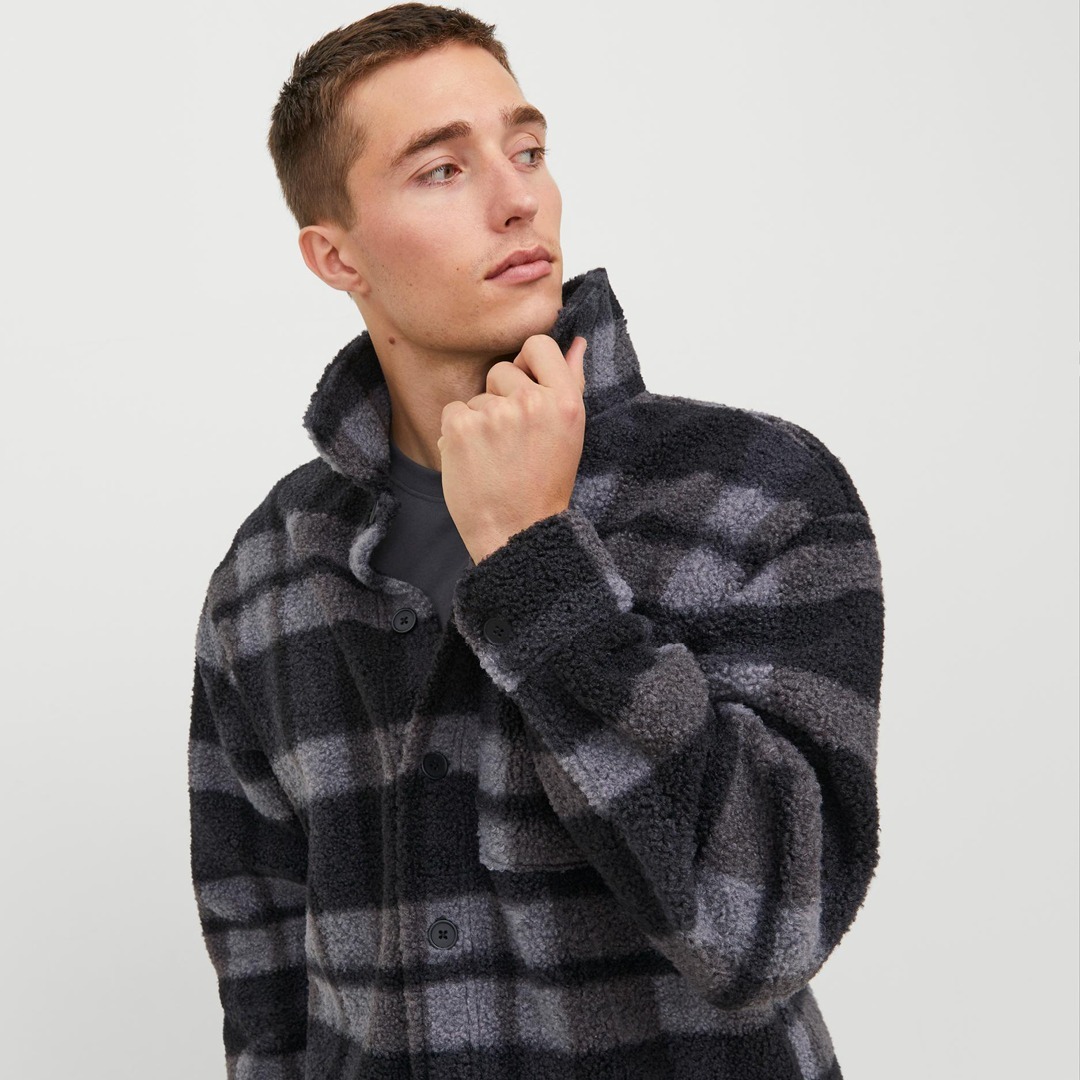 Ein Mann trägt eine karierten, flauschigen Jacke in Schwarz- und Grautönen. Ein Mann trägt eine karierten, flauschigen Jacke in Schwarz- und Grautönen.