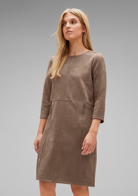 Eine Frau trägt ein braunes Kleid mit langen Ärmeln und Reißverschlusstaschen. Eine Frau trägt ein braunes Kleid mit langen Ärmeln und Reißverschlusstaschen.