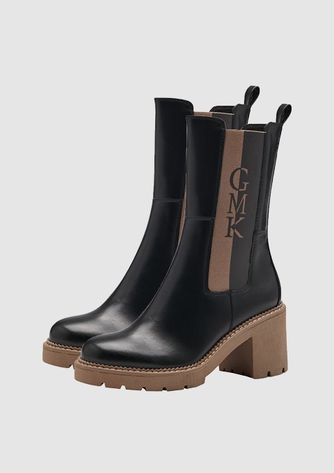 Schwarze Stiefel mit blockiertem Absatz und einem braunen Einsatz mit der Aufschrift "GMK".