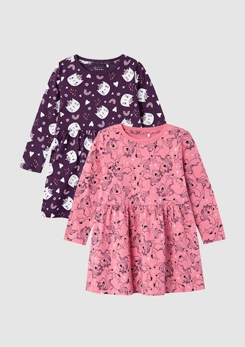 Zwei Mädchenkleider, eines in lila mit Katzenmotiven und das andere in rosa mit Einhornmotiven. Zwei Mädchenkleider, eines in lila mit Katzenmotiven und das andere in rosa mit Einhornmotiven.