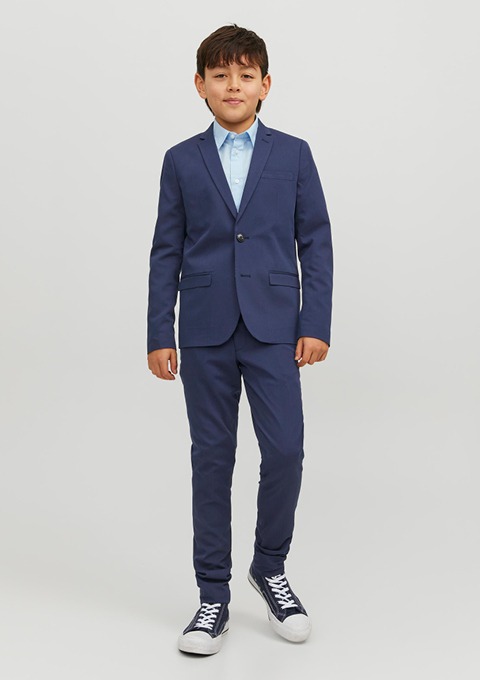 Ein Junge in einem blauen Anzug mit einem hellblauen Hemd und Sneakers. Ein Junge in einem blauen Anzug mit einem hellblauen Hemd und Sneakers.