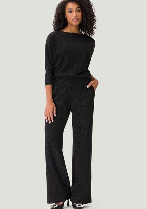 Eine Frau trägt einen eleganten, schwarzen Overall mit weitem Bein und einem glitzernden Oberteil. Eine Frau trägt einen eleganten, schwarzen Overall mit weitem Bein und einem glitzernden Oberteil.