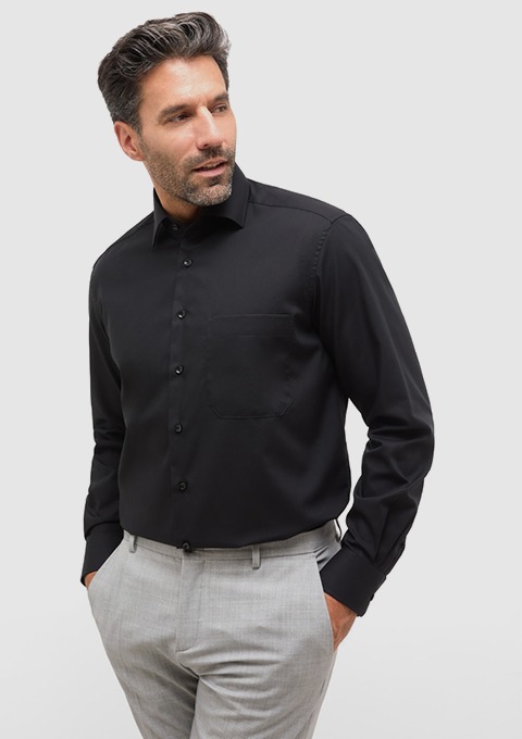 Ein Mann trägt ein schwarzes Hemd und hellgraue Hosen. Ein Mann trägt ein schwarzes Hemd und hellgraue Hosen.