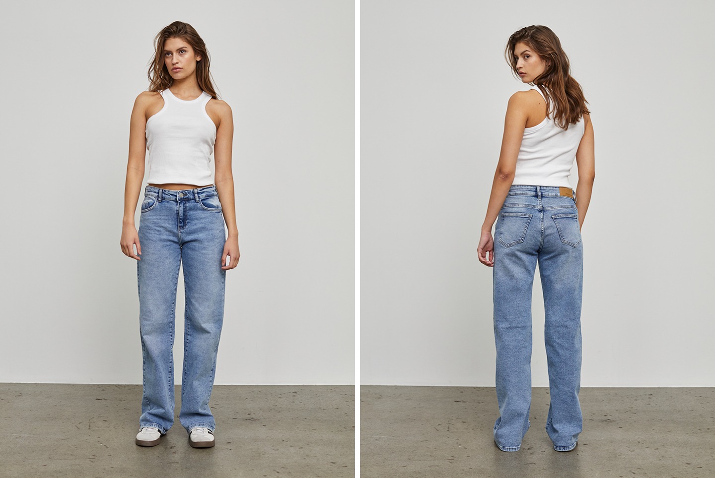 Eine Frau trägt ein weißes Trägershirt und blaue Jeans. Sie steht frontal und seitlich zur Kamera.