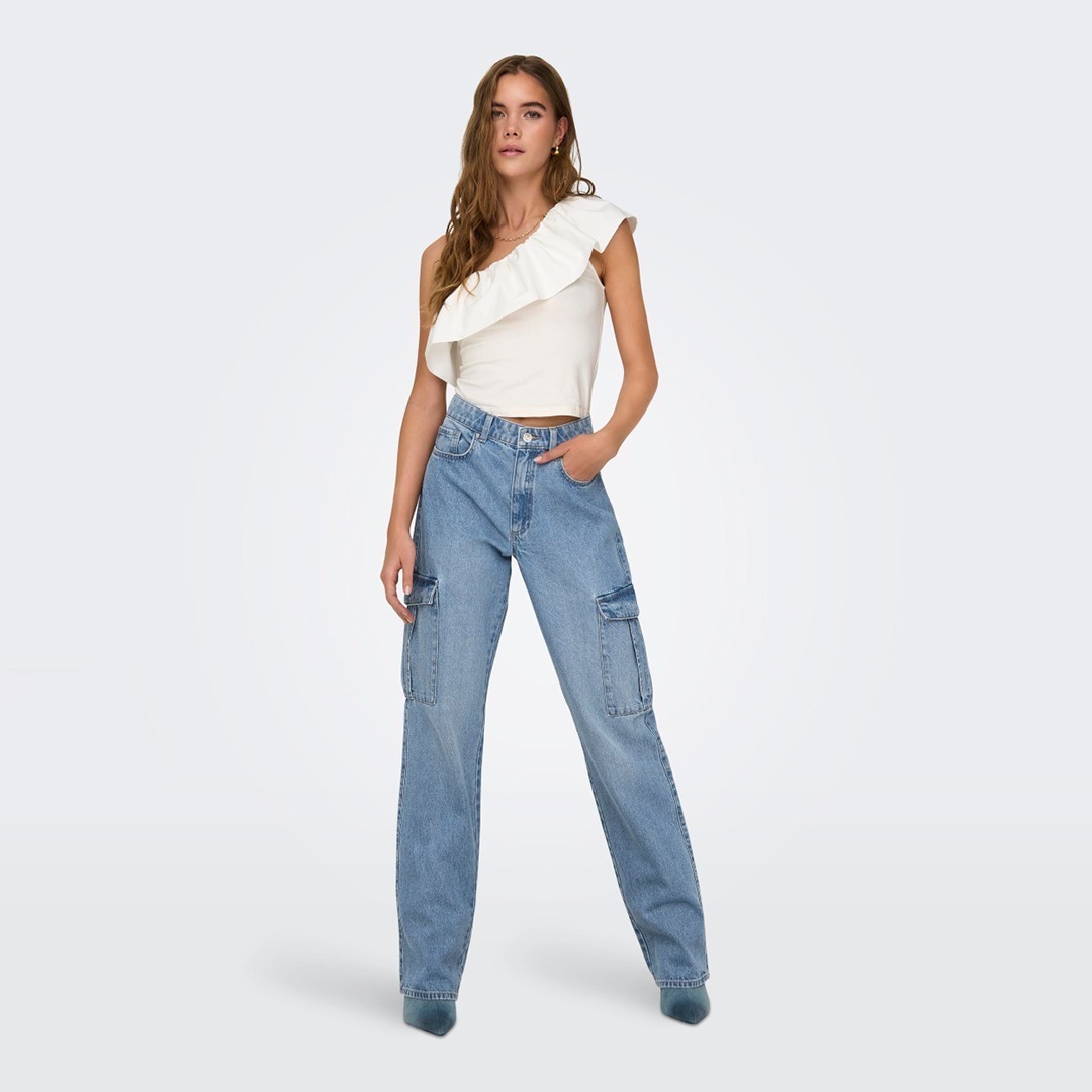 Eine Frau trägt ein ärmelloses Oberteil mit Rüsche und weite Cargo-Jeans.