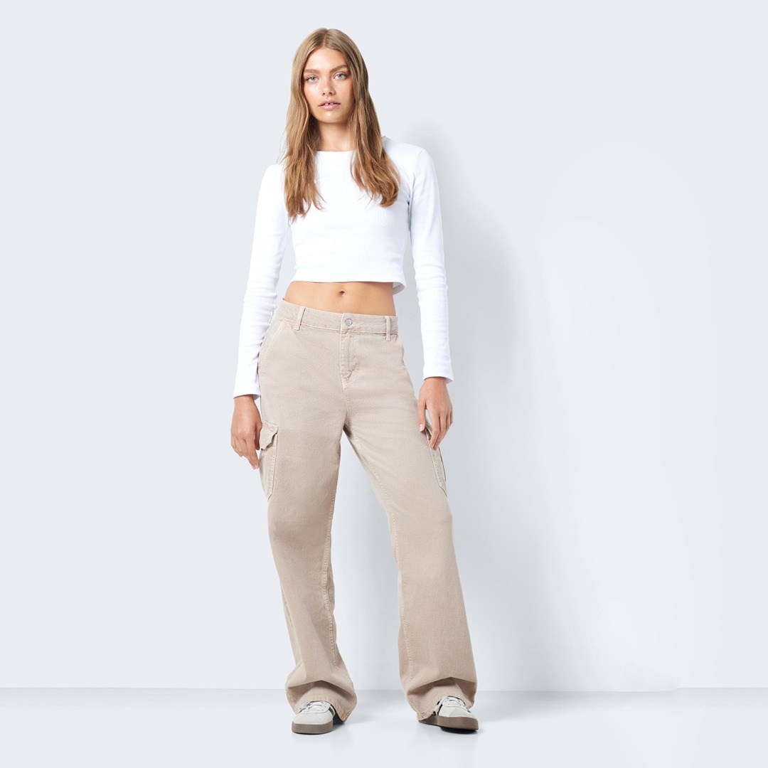 Eine Frau trägt einen langen, weißen Crop-Top und beige Cargo-Hosen.