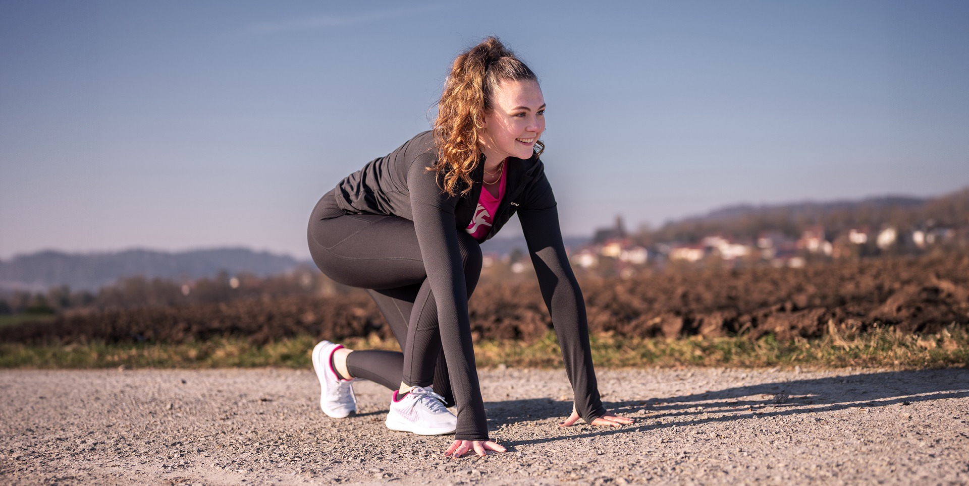 Eine junge Frau in Sportkleidung bereitet sich auf einen Lauf vor.