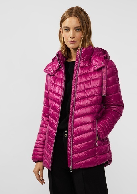 Eine Frau trägt eine pinke, gepolsterte Jacke mit Kapuze.