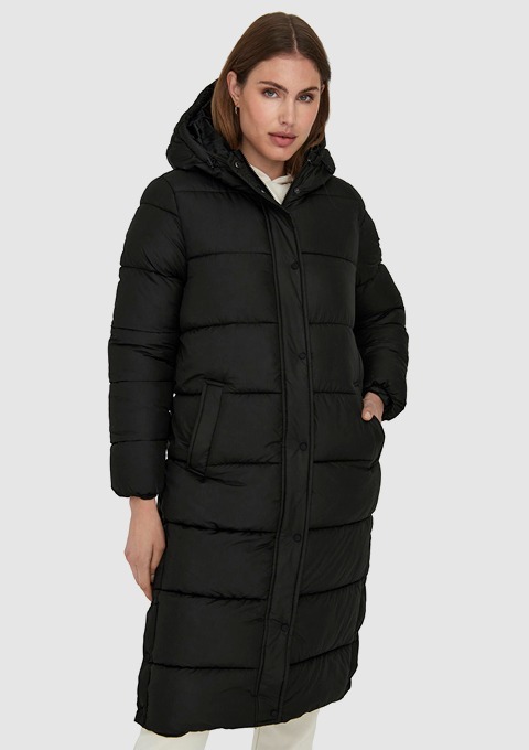 Eine Frau trägt einen langen, schwarzen, gepolsterten Wintermantel mit Kapuze.
