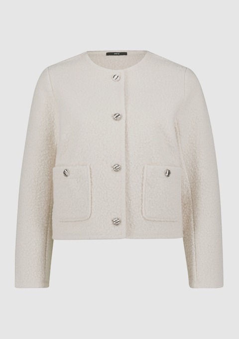 Ein hellbeige Jackett mit runden Taschen und Knöpfen. Ein hellbeige Jackett mit runden Taschen und Knöpfen.