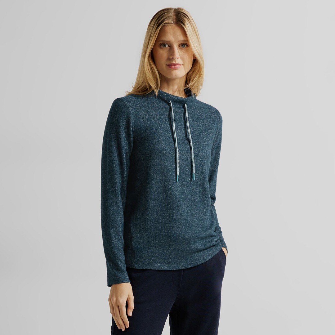 Eine Frau trägt einen blauen Pullover mit Kapuze und langen Ärmeln.