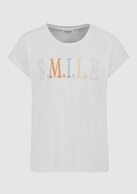 Ein weißes T-Shirt mit dem Aufdruck „S.M.I.L.E.“ in bunten Buchstaben. Ein weißes T-Shirt mit dem Aufdruck "S.M.I.L.E." in bunten Buchstaben.