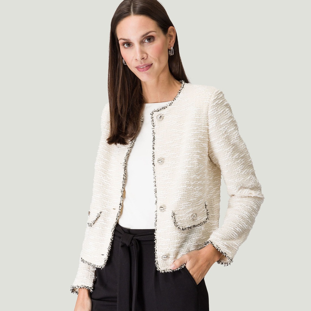 Eine Frau trägt eine elegante, weiße Jacke mit Knöpfen und schwarzen Akzenten. Eine Frau trägt eine elegante, weiße Jacke mit Knöpfen und schwarzen Akzenten.