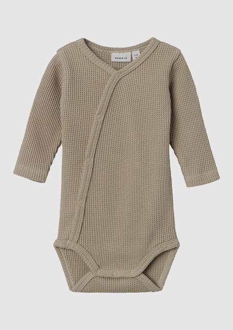 Ein beiger Babystrampler mit langen Ärmeln und Wickelverschluss. Ein beiger Babystrampler mit langen Ärmeln und Wickelverschluss.