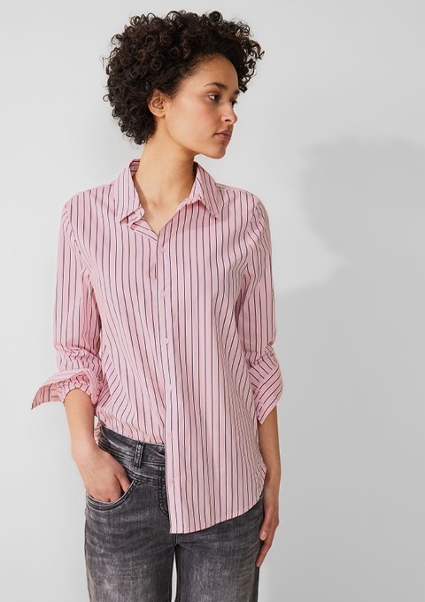 Eine Person trägt ein gestreiftes, rosa Hemd und graue Jeans. Eine Person trägt ein gestreiftes, rosa Hemd und graue Jeans.