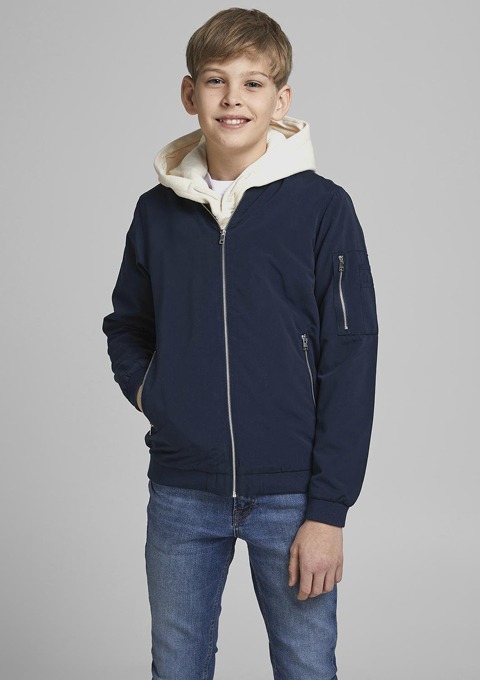 Ein Junge trägt eine navyblaue Jacke mit Kapuze und einen weißen Hoodie darunter, dazu eine Jeans. Ein Junge trägt eine navyblaue Jacke mit Kapuze und einen weißen Hoodie darunter, dazu eine Jeans.