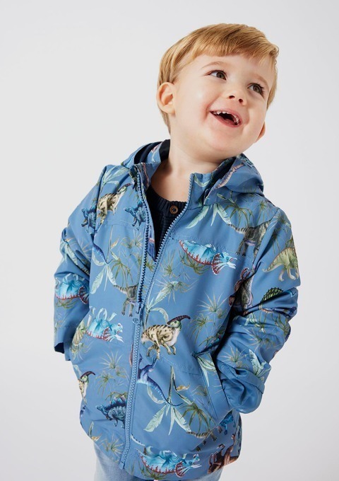 Ein lächelndes Kind in einer blauen Jacke mit Dinosaurier-Muster. Ein lächelndes Kind in einer blauen Jacke mit Dinosaurier-Muster.