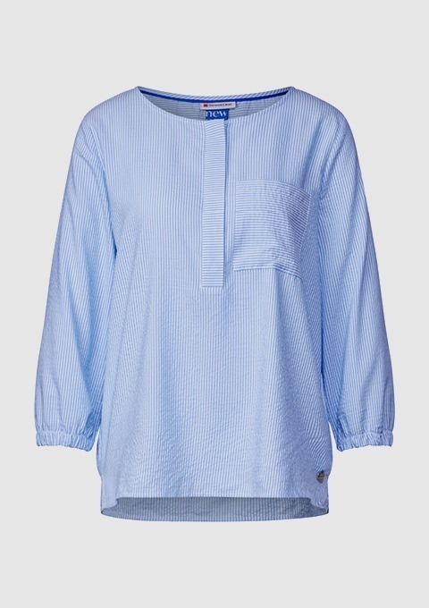 Blau-gestreifte Bluse mit langen Ärmeln und Brusttasche. Blau-gestreifte Bluse mit langen Ärmeln und Brusttasche.