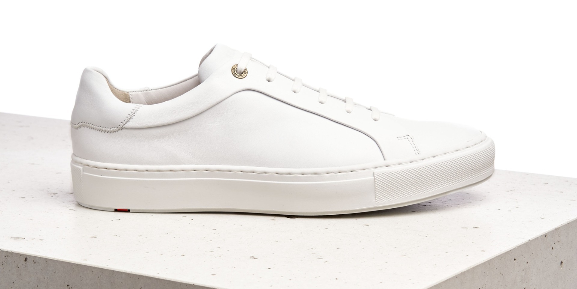 Weißer Sneaker auf einer hellen Oberfläche.