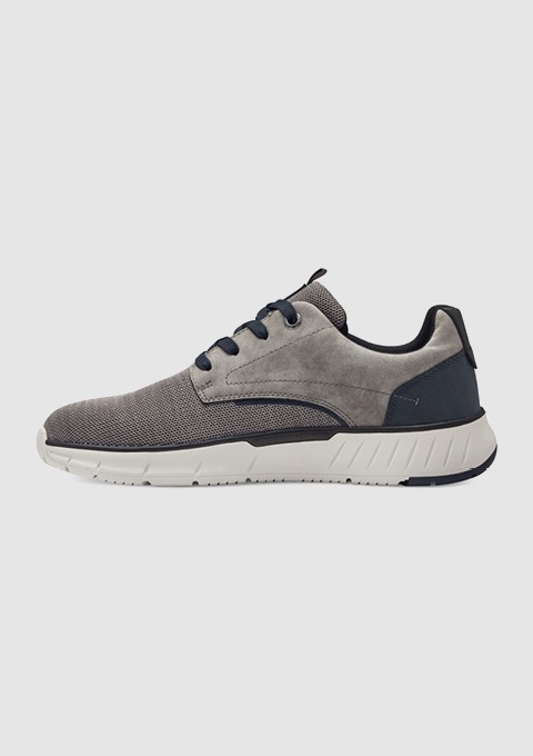Ein grauer Sneaker mit blauen Akzenten und einer weißen Sohle.