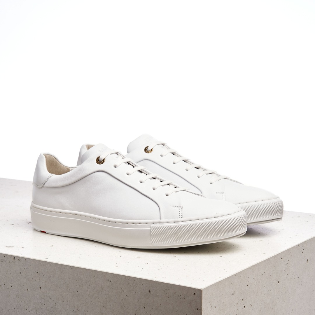 Weiße Sneakers auf einem hellen Untergrund.