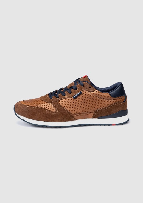 Ein brauner Sneaker aus Wildleder und Stoff mit blauen Akzenten.