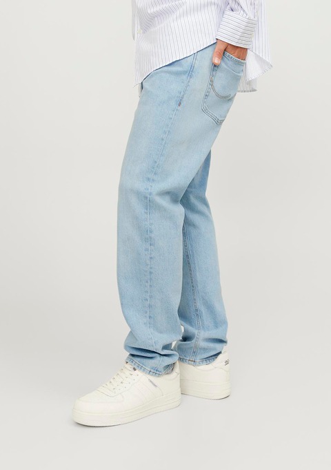 Eine Person trägt eine lockere, hellblaue Jeans und weiße Sneaker. Eine Person trägt eine lockere, hellblaue Jeans und weiße Sneaker.