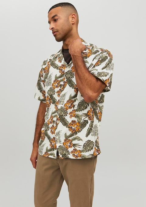 Ein Mann trägt ein hawaiianisches Hemd mit einem Blumen- und Blattmuster.