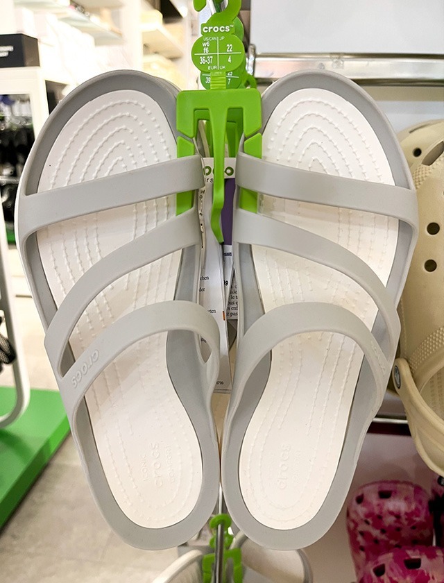 Graue Crocs-Sandalen mit mehreren Riemen, aufgehängt im Geschäft.