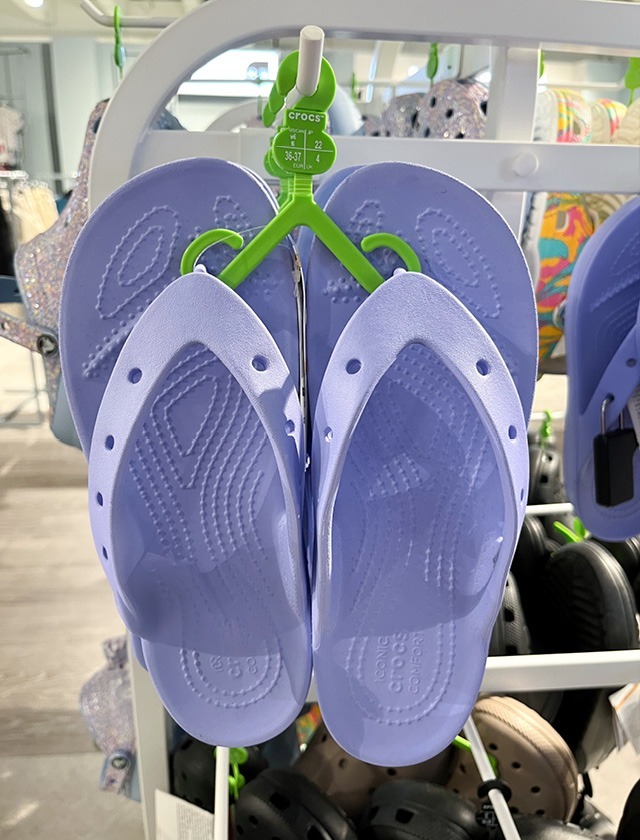 Lila Crocs-Schuhe, die an einem Verkaufsdisplay hängen.