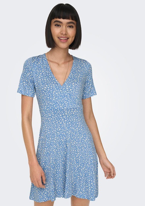 Eine Frau trägt ein blaues, kurzärmeliges Kleid mit Blumenmuster.