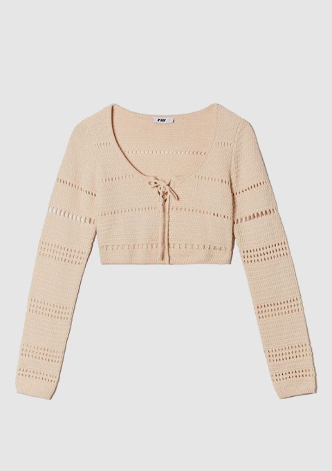 Ein beigefarbener, langsärmeliger, cropped Pullover mit Lochmuster.