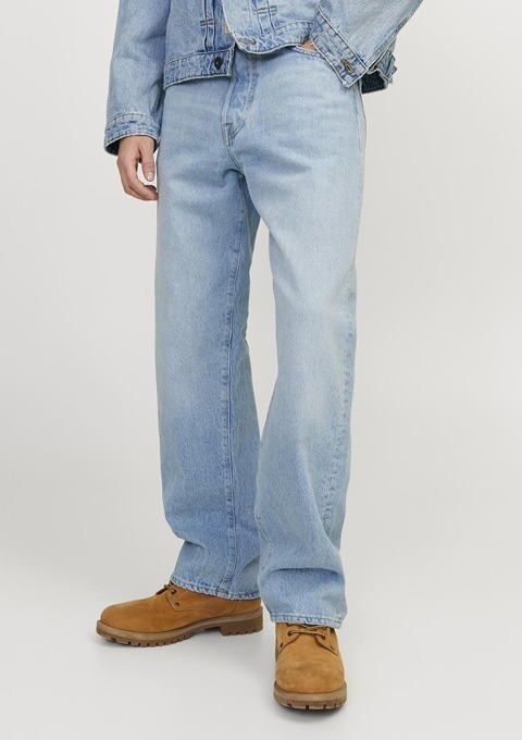 Eine Person trägt eine blaue Jeans, ein Jeansjackett und braune Schuhe. Eine Person trägt eine blaue Jeans, ein Jeansjackett und braune Schuhe.