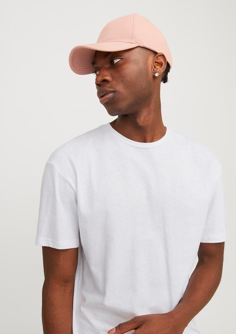 Ein junger Mann trägt ein weißes T-Shirt und eine rosa Cap. Ein junger Mann trägt ein weißes T-Shirt und eine rosa Cap.