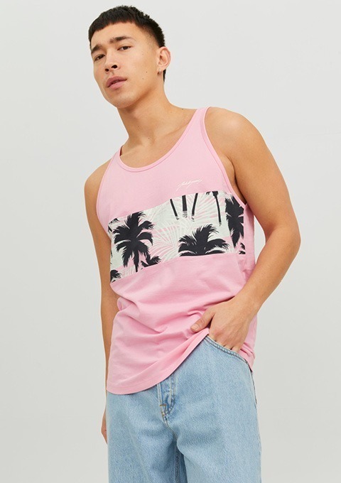 Ein Mann trägt ein pinkes Tanktop mit einem Palmenmuster in der Mitte und blauen Jeans.