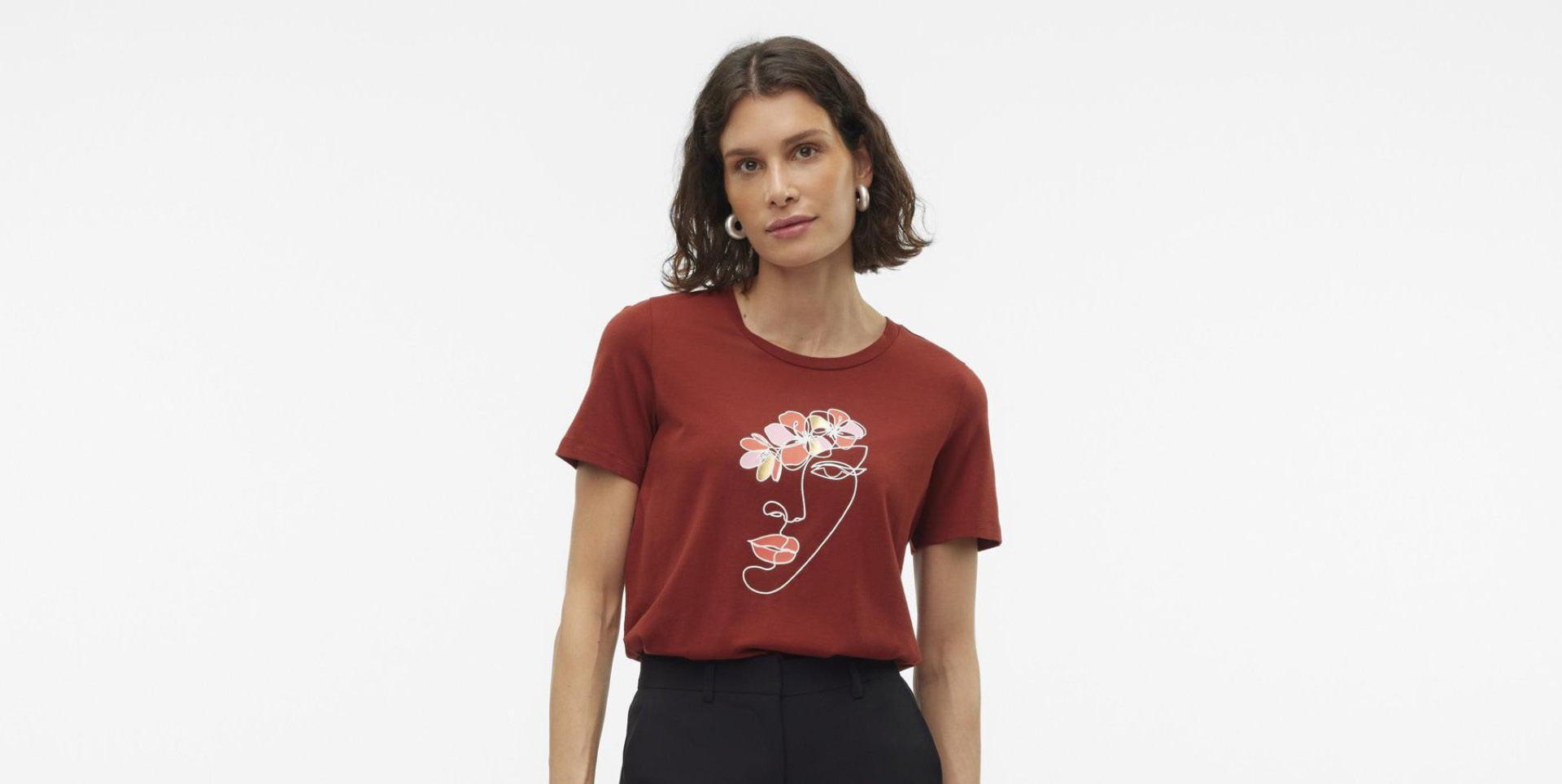 Eine Frau trägt ein rotes T-Shirt mit einem floralen Gesichtsmotiv. Eine Frau trägt ein rotes T-Shirt mit einem floralen Gesichtsmotiv.