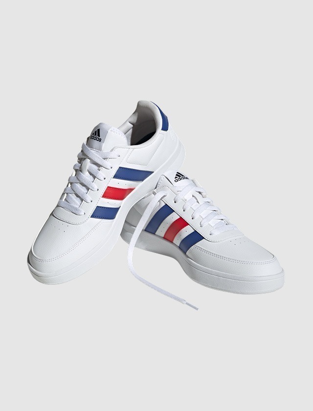 Weißes Paar Sneakers mit roten und blauen Streifen.