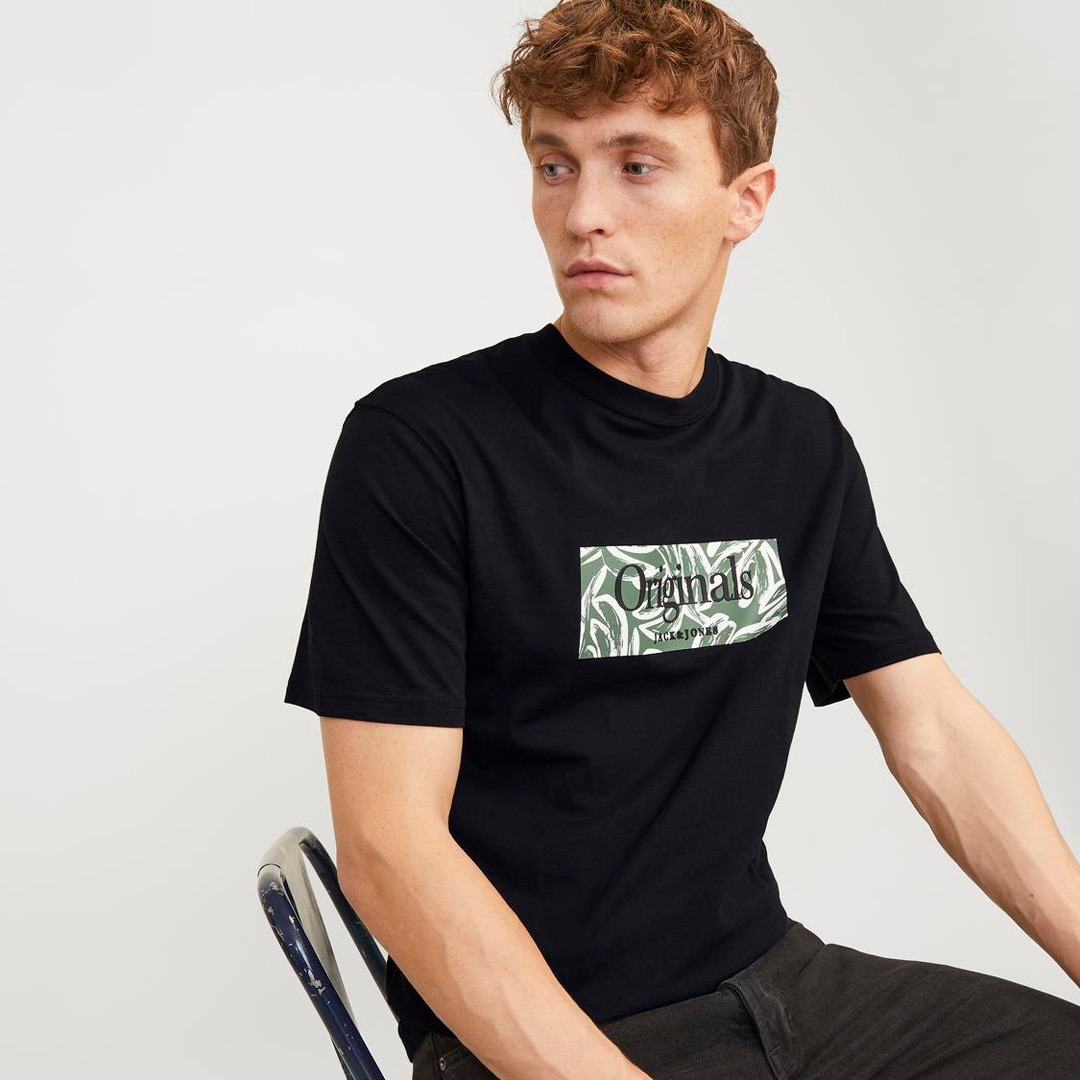 Ein Mann trägt ein schwarzes T-Shirt mit einem grßnen Logo in der Mitte. Ein Mann trägt ein schwarzes T-Shirt mit einem grßnen Logo in der Mitte.