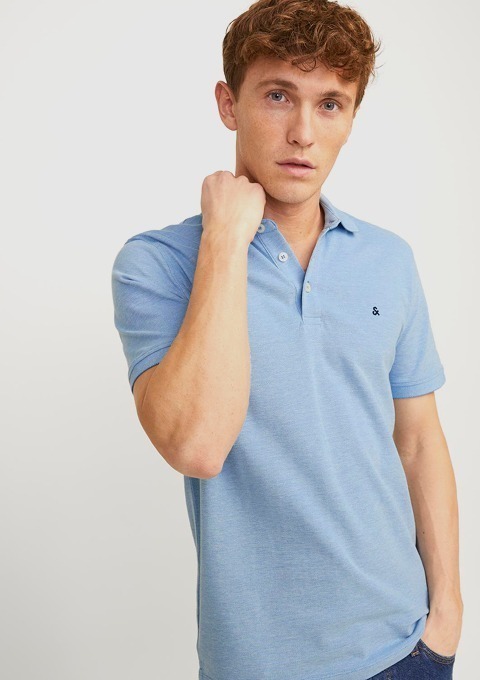 Ein Mann trägt ein hellblaues Polo-Shirt und schaut direkt in die Kamera.