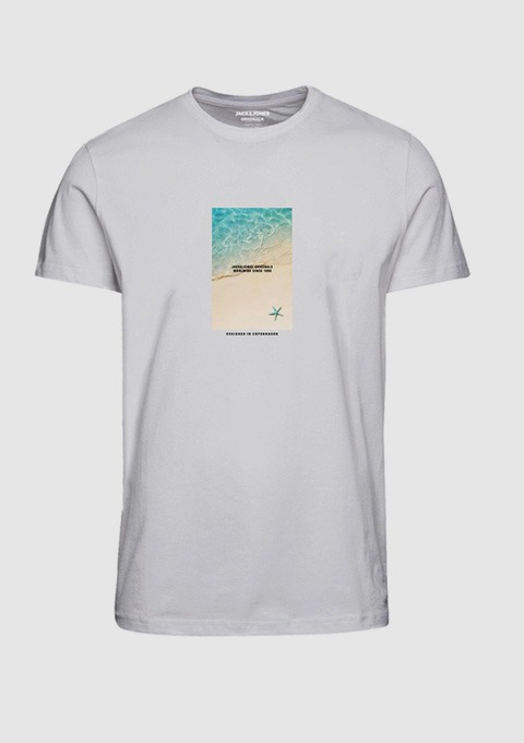 Ein weißes T-Shirt mit einem bunten Druck, der Wasser und Sand zeigt, sowie einem Text in der Mitte.