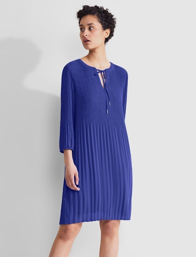Ein Kleid in Blau mit Plissee und einem Rundhalsausschnitt, das bis zu den Knien reicht.