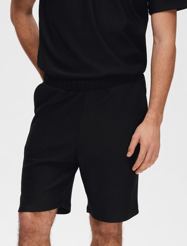 Ein Mann trägt ein schwarzes Oberteil und passende Shorts. Ein Mann trägt ein schwarzes Oberteil und passende Shorts.