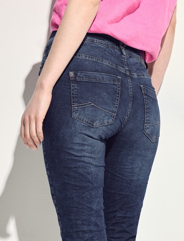 Eine Person trägt eine pinke Bluse und enge, dunkelblaue Jeans. Eine Person trägt eine pinke Bluse und enge, dunkelblaue Jeans.