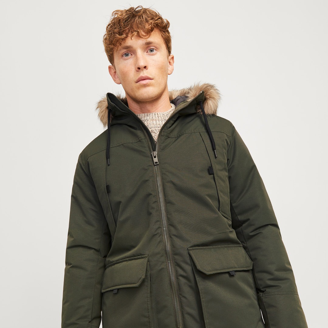 Ein Mann trägt eine grüne Winterjacke mit Kapuze und Kunstpelzbesatz. Ein Mann trägt eine grüne Winterjacke mit Kapuze und Kunstpelzbesatz.