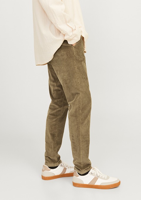 Eine Person trägt eine bequeme, olivgrüne Cordhose und modische Sneakers.