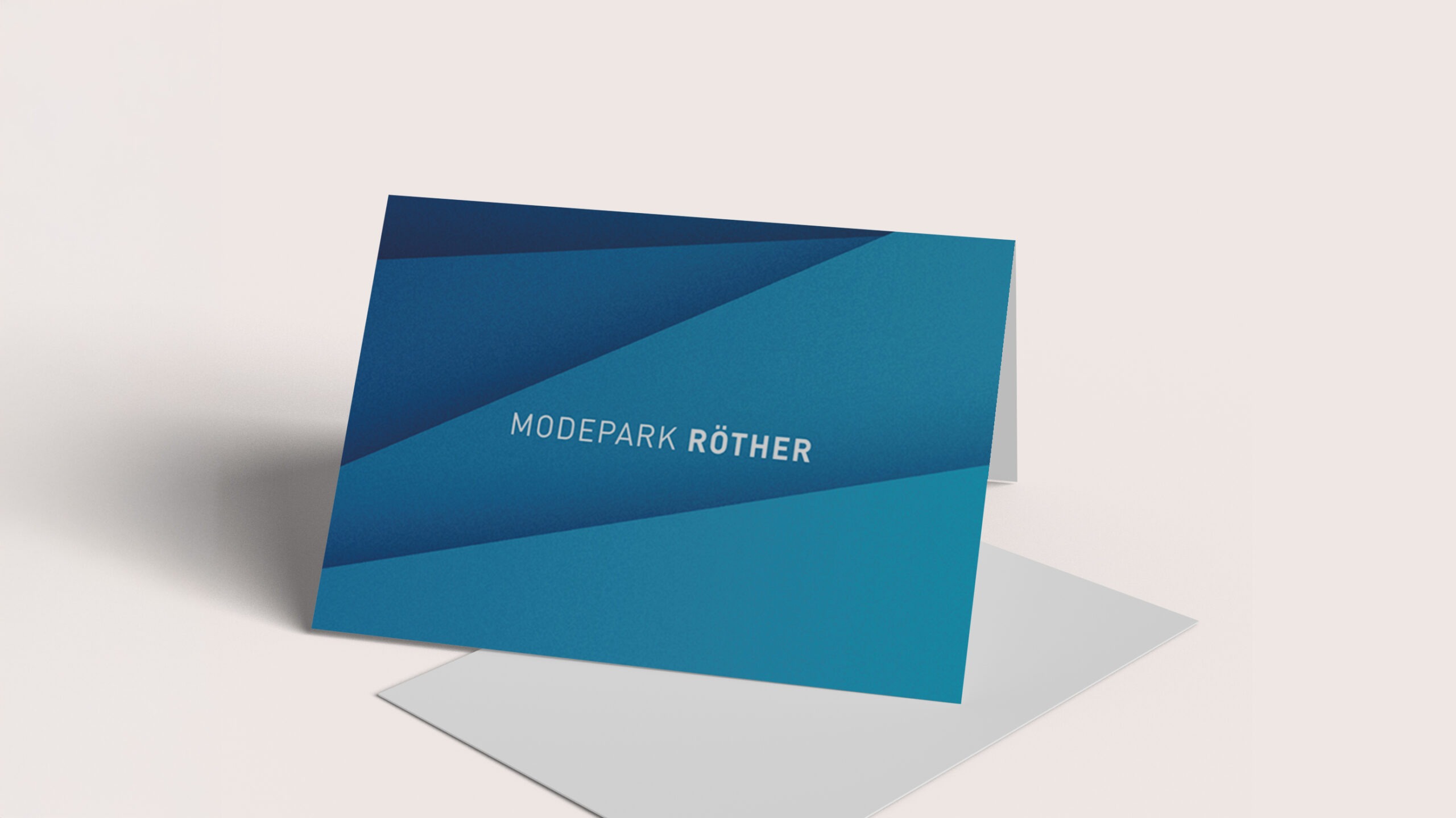 Ein gefalteter Kartenständer in Blau mit der Aufschrift "MODE PARK RÖTHER".
