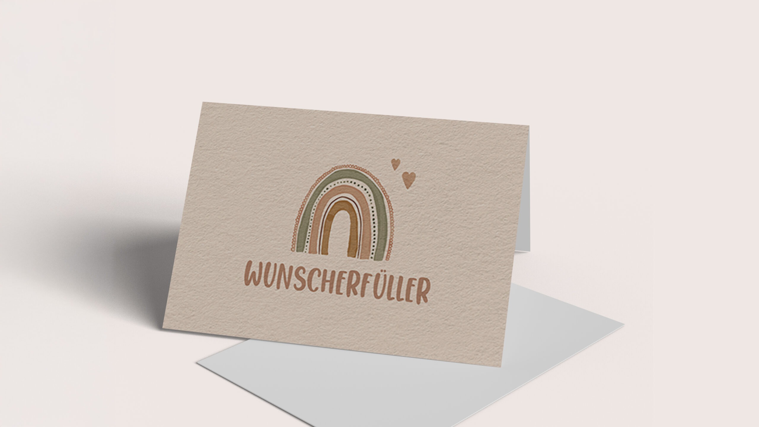 Eine beige Karte mit dem Text "Wunscherfüller" und einem bunten Regenbogen sowie kleinen Herzen.